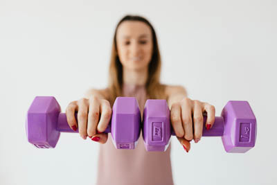 kader_400-purple-dumbbells-in-hands-of-positive-sportswoman-4498294